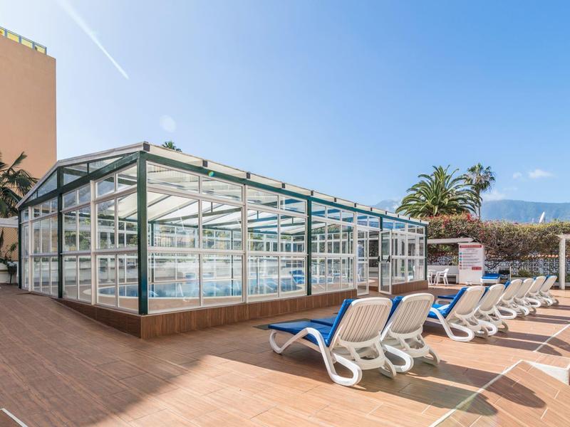 Area piscina con piscina coperta e lettini sotto un cielo limpido