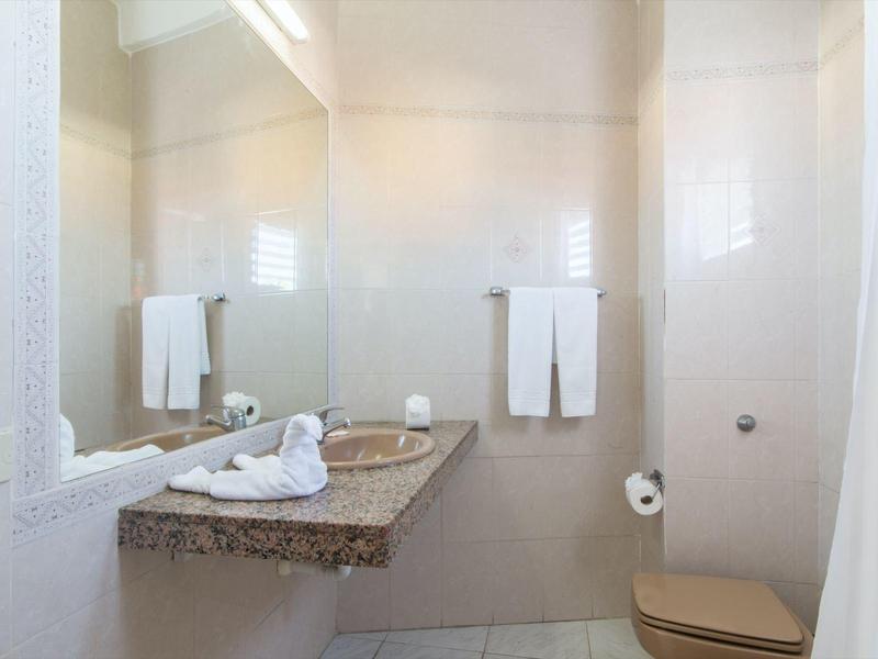 Bagno luminoso con asciugamani piegati su piano in granito e pareti bianche.