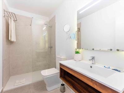 Nowoczesna hotelowa łazienka z prysznicem, toaletą i dużą umywalką z drewnianą szafką.