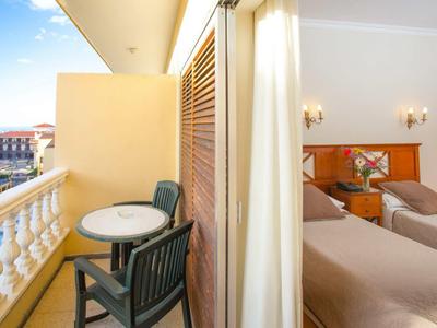 Balcone con tavolo e due sedie accanto a una camera con due letti.