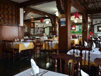 Przytulna część restauracyjna z drewnianymi meblami, nakrytymi stołami i rustykalnym wystrojem.