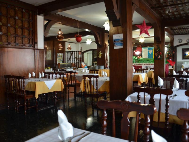 Gezellige rustieke eetkamer met houten lambrisering, witte tafelkleden en gedempt licht.