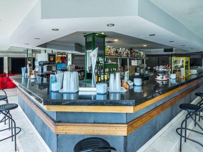 Espace bar moderne avec tabourets noirs et coussins rouges dans un hôtel.