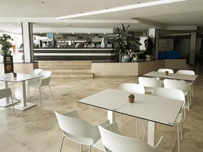 Espace de restauration intérieur moderne avec tables et chaises blanches dans un cadre lumineux.
