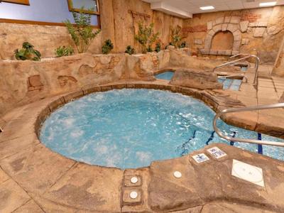 Un jacuzzi rond avec de l'eau bleue bouillonnante, entouré de revêtement en pierre à l'intérieur.