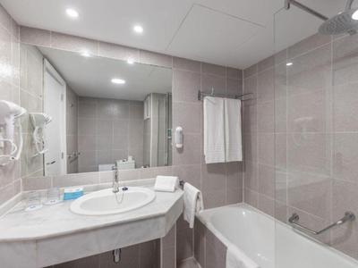 Salle de bain moderne avec lavabo, baignoire, miroir et serviettes aux tons neutres.