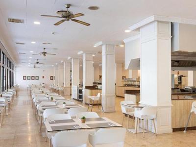 Restaurant lumineux et moderne avec tables blanches, chaises et grandes fenêtres dans un Reiseumfeld.