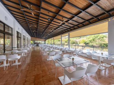 Espace extérieur couvert d'un restaurant avec tables et chaises blanches au bord d'une rivière.