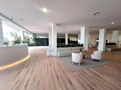 Hall d'hôtel moderne avec sol en bois clair et coin salon avec fauteuils.