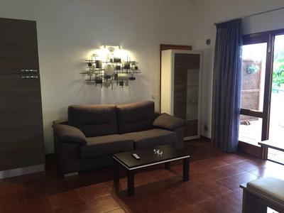 Cozy hotel room with sofa, table, mirror, and open balcony with curtains.