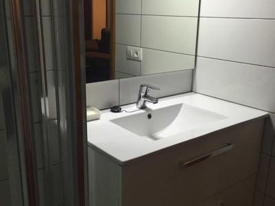 Modern bathroom with white sink and mirrored wall.