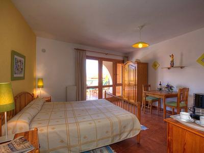 Gemütliches Schlafzimmer mit Doppelbett, Holzmöbeln, Balkon und warmem Licht.