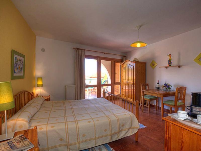 Gemütliches Schlafzimmer mit Doppelbett, Holzmöbeln, Balkon und warmem Licht.