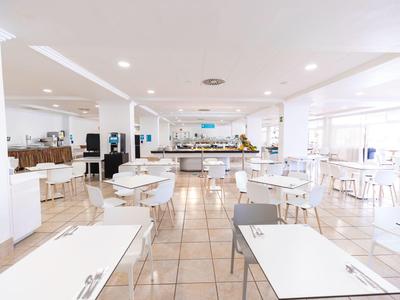 Salle à manger lumineuse et moderne avec tables et chaises blanches dans un hôtel.