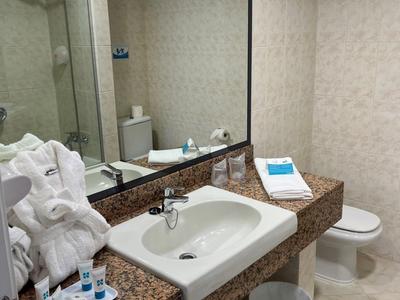 Une salle de bain moderne avec lavabo, grand miroir et toilette propre.