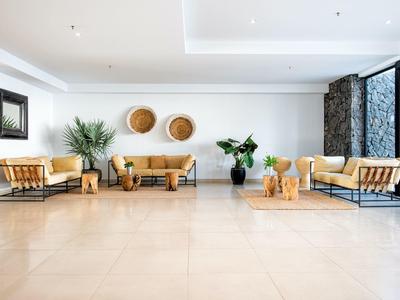 Helles Wohnzimmer mit beigem Sofa, Pflanzen, Holzdekoration und großem Fenster.