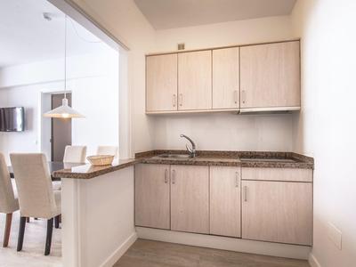 Mała nowoczesna kuchnia z jasnymi drewnianymi szafkami i granitowym blatem.