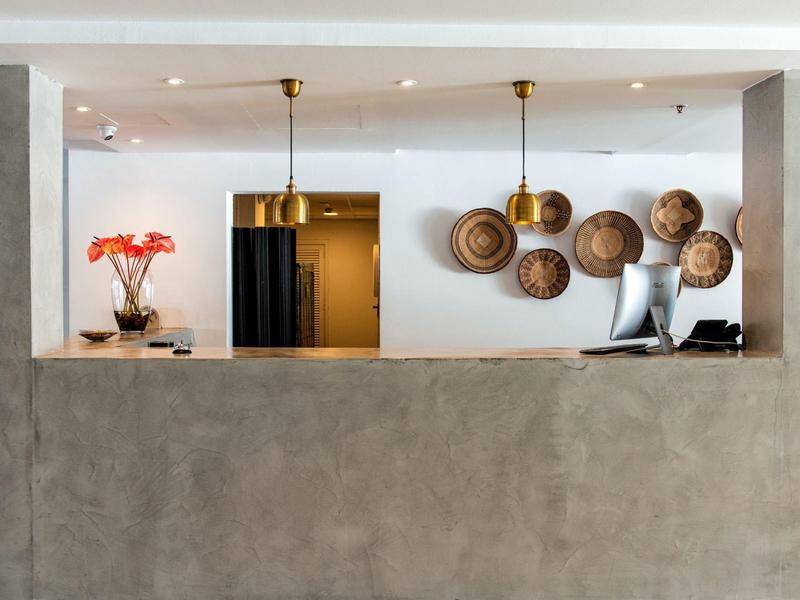 Minimalistyczna recepcja hotelowa z betonową ścianą, ladą recepcyjną i dekoracyjnymi koszami na ścianie.