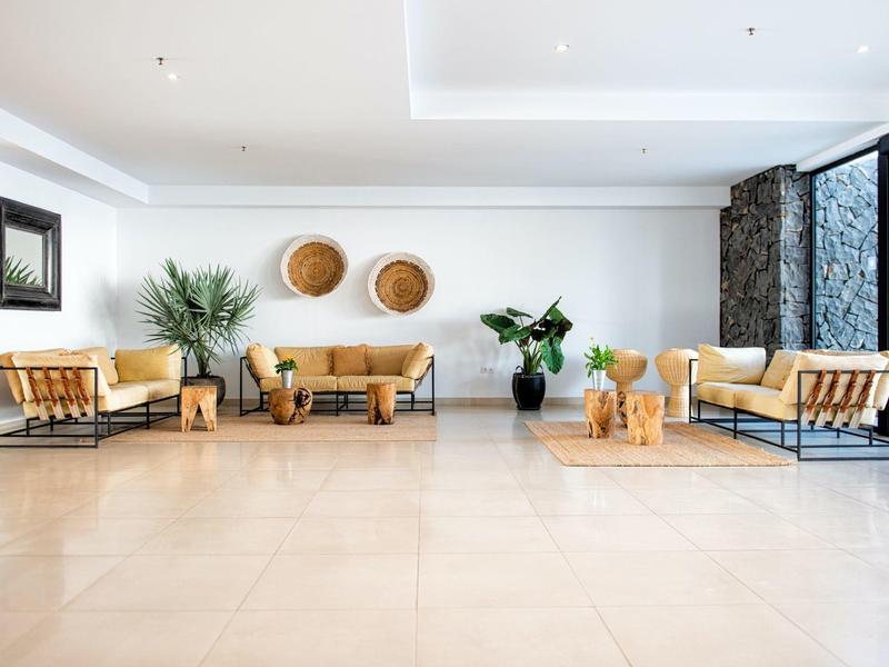 Jasna, nowoczesna lobby hotelowa z wygodnymi skórzanymi fotelami, roślinami i dekoracjami ściennymi.