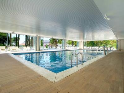 Piscine couverte avec carrelage en bois et vue sur le jardin dans un hôtel.