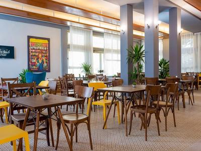 Un restaurant spacieux et lumineux avec des tables en bois et des chaises colorées, aménagé de manière moderne.