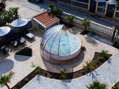 Bain à remous rond avec couvercle en dôme partiellement ouvert dans un espace extérieur paysager.