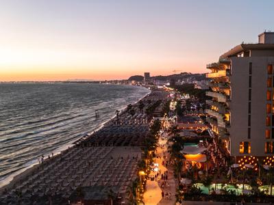 Lang strand bij zonsondergang met verlichte hotels en promenade langs de kust.