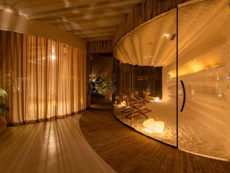 Moderne Sauna mit großen Glaswänden, warmem Licht, Holzverkleidung und Pflanzen im Innenraum.