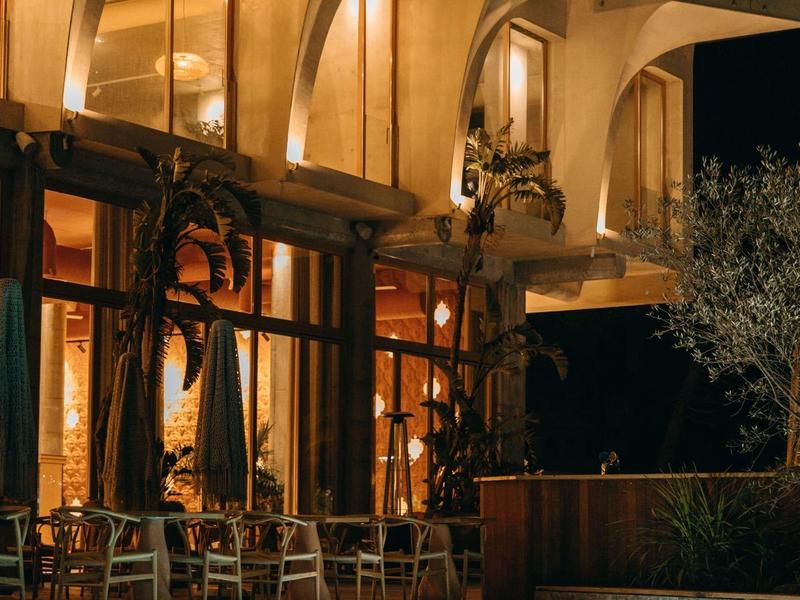 Beleuchtetes modernes Gebäude mit Balkon und blauem Pool bei Nacht.