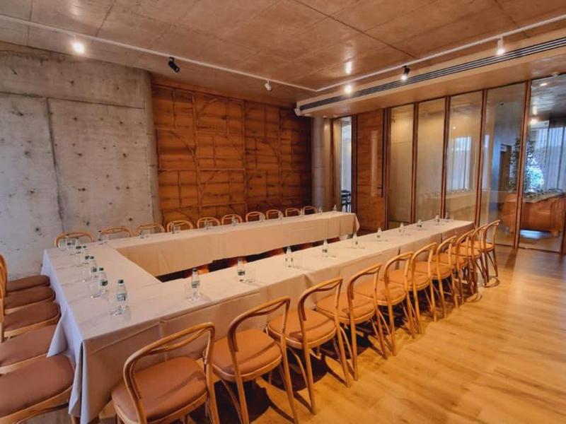 Moderner Konferenzraum mit langem Tisch, Holzstühlen und einer Kombination aus Beton- und Holzwänden.