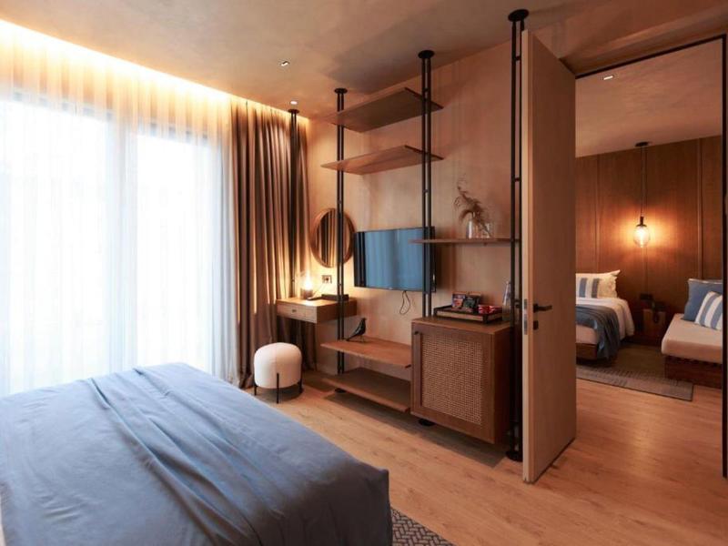 Modernes Schlafzimmer mit Holzregalen, Bett, großem Fenster und angrenzendem Wohnzimmer.