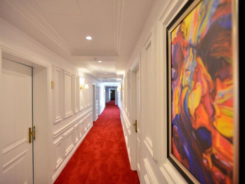 Langer weißer Flur mit rotem Teppich und farbigem Gemälde an der rechten Wand.