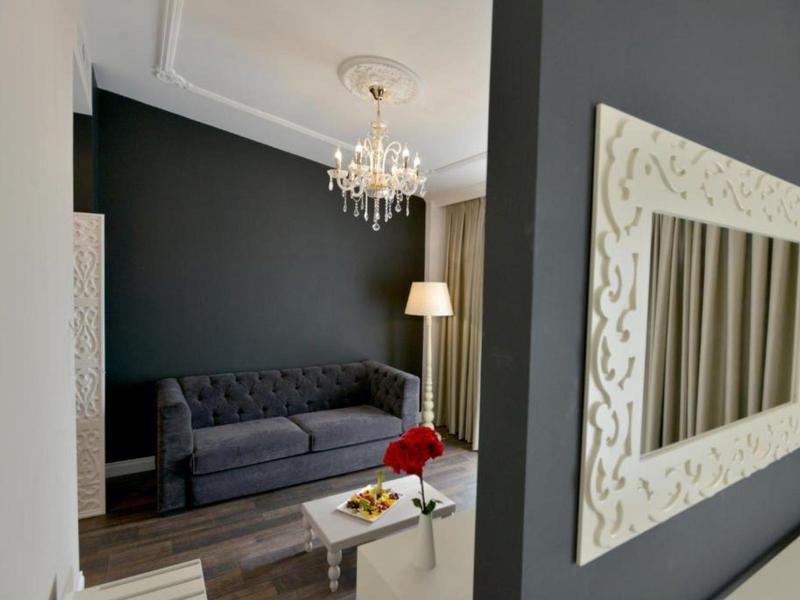 Moderner Wohnraum mit grauer Wand, Sofa, Stehlampe, Kronleuchter und einem Spiegel mit weißem Rahmen.