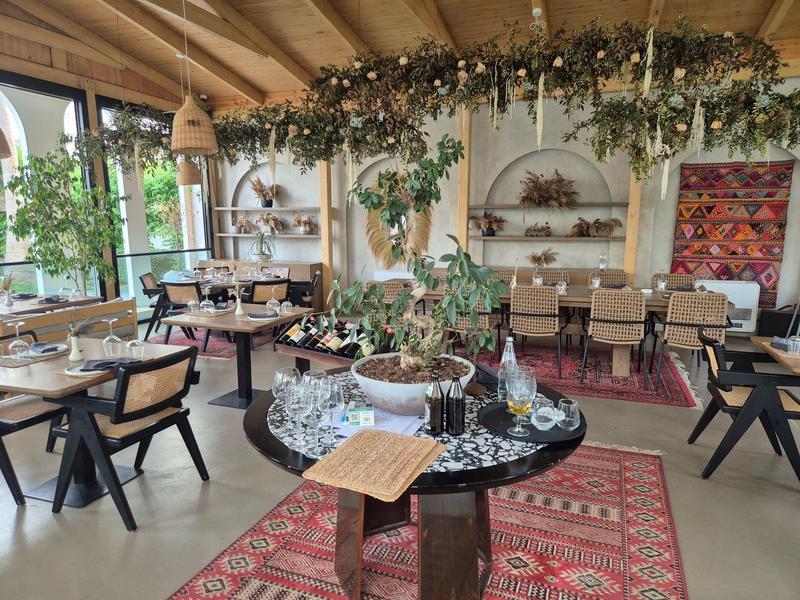 Gemütliches Restaurant mit Holzdecke, Pflanzen an der Decke und Teppichen auf dem Boden.
