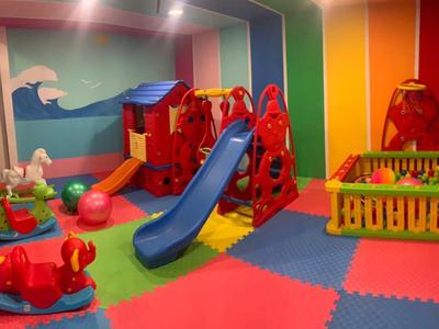 Bunter Indoor-Kinderspielraum mit Rutsche, Bällebad, Spielzeugpferden und weichem Bodenbelag.