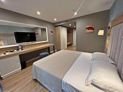 Modernes Hotelzimmer mit großem Bett, Schreibtisch und Fernseher an der Wand.