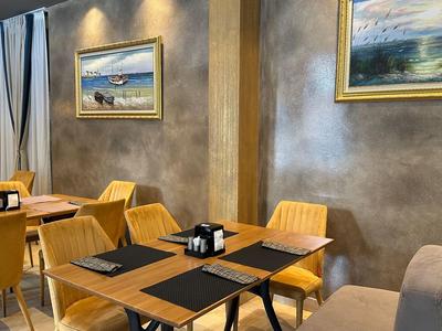 Ristorante moderno con sedie gialle, tovagliette nere e opere d'arte alle pareti.