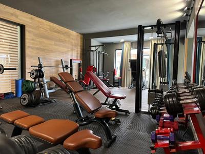 Fitnessraum mit verschiedenen Trainingsgeräten und verstellbaren Bänken in einem Hotel.