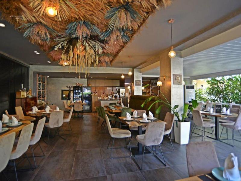 Modernes Restaurant mit gemütlichen Sitzgelegenheiten und großen Fenstern, die einen Blick ins Freie erlauben.