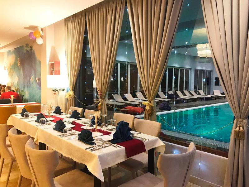 Eleganter Speiseraum mit gedecktem Tisch und Blick auf einen Innenpool und Liegestühle.