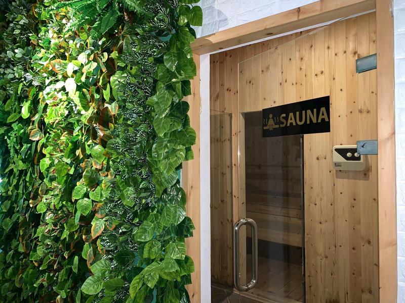 Holzsaunatür neben einer grünen Pflanzenwand in einem Wellnessbereich