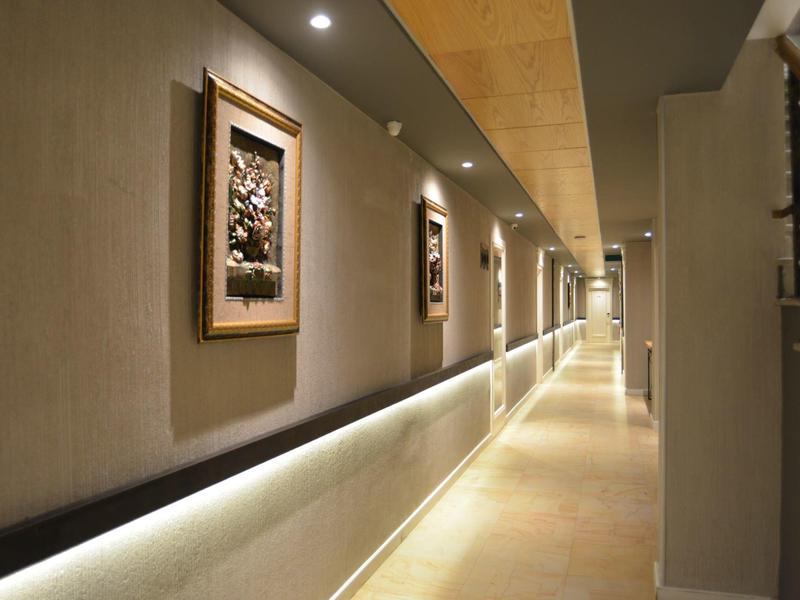 Beleuchteter Hotelflur mit modernen Gemälden und Treppe an der Seite.