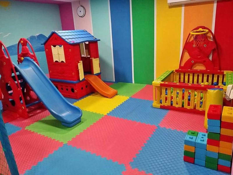 Bunter Innen-Spielraum mit Rutsche, Klettergerüst, Bällebad und großen Bauklötzen auf Matte.