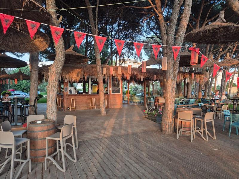 Offene Bar mit Holzmöbeln und roten Wimpeln in tropischer Umgebung.