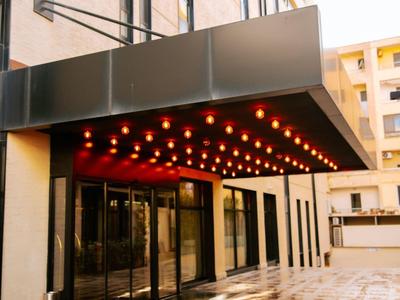 Vchod do hotelu s osvětlenou markýzou a lesklou podlahou.