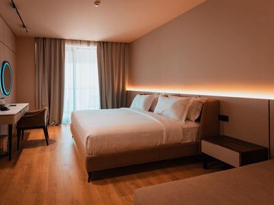 Modern hotel room with large bed, desk, and indirect wall lighting