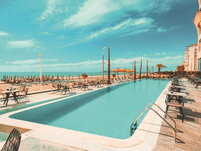 Modern pool area with loungers and sea view at a hotel.
