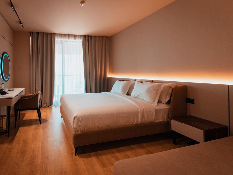 Modern hotel room with large bed, desk, and indirect wall lighting