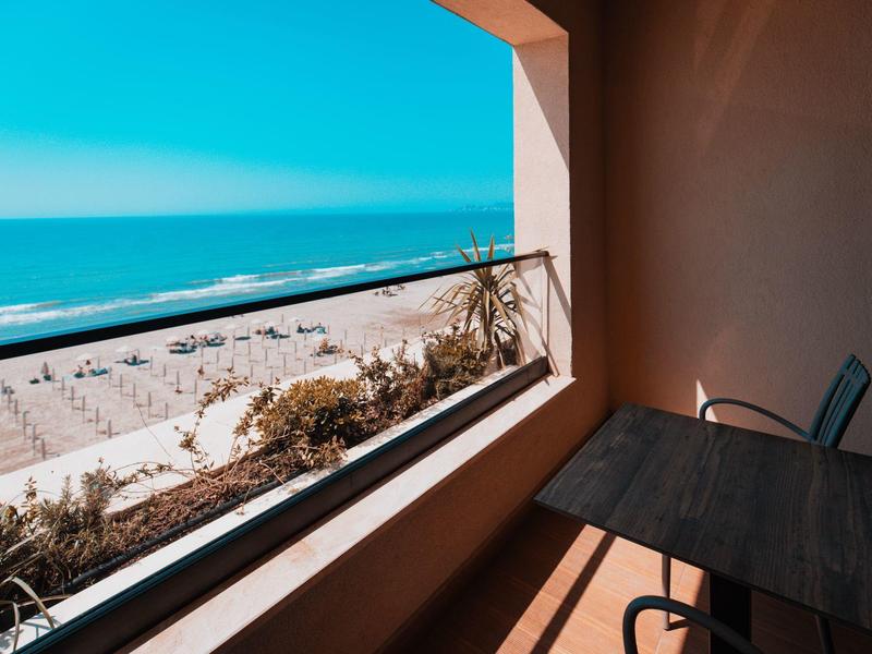 View from a balcony overlooking a beach with umbrellas and blue sea.
