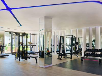 Moderner Fitnessraum mit Gewichten, Kraftgeräten und großen Fenstern